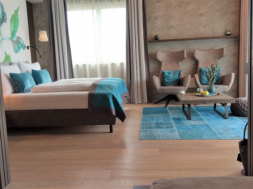 la maiena meran resort: Die gediegene Farbgebung und der edle Holzboden mit elegantem Design-Teppich im Wohnbereich fallen uns gleich ins Auge
