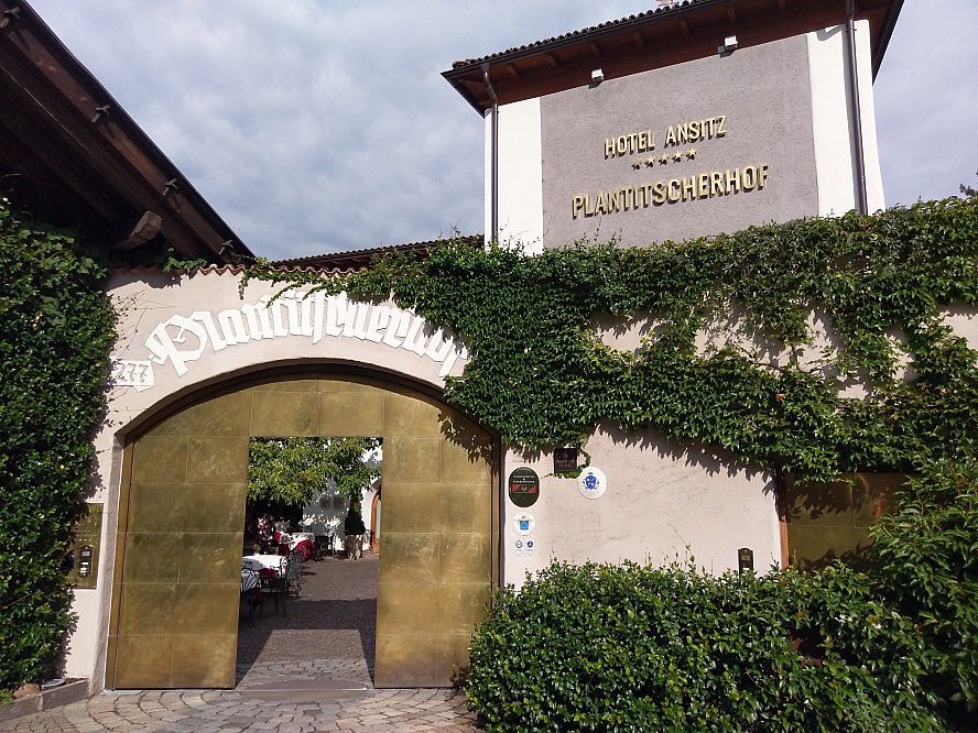 Hotel Ansitz Plantitscherhof: Beim Eintreten durch ein goldenes Tor eröffnet sich uns ein romantischer Innenhof mit seinen schattigen Tischchen